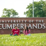 Two students relax in front of Cumberlands welcome sign 