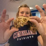 A student displays a woodcraft she made in the library maker space. 