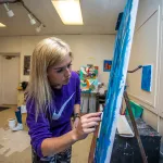 An art student works on a painting in the studio. 