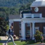 A student walks on campus in front of the science building. 