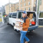 A student carries donated food into a food pantry. 
