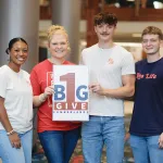 Students hold a sign promoting give day. 
