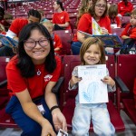 An international student helps an elementary student with a coloring. 