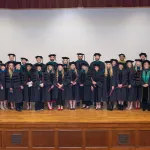 The first graduating class from the DPT program post on stage for a photo. 