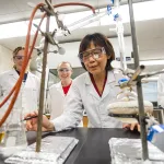 A chemistry professor shows an experiment to students in a lab.