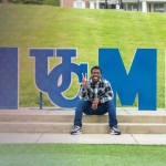 A student sits by the Home sign on campus.