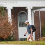 A student walks to class with his backpack. 
