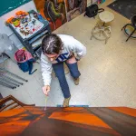 A male art student works on an abstract canvas. 