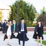 Graduates walk across the campus quad. 