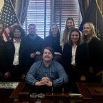 Students from the Upsilon Upsilon honor society at Cumberlands pose behind a desk. 