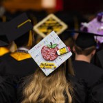 A decorated graduation hat with a teacher motif. 