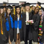 Six female graduates pose in cap and gown following the commencement service. 