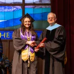 A female honors student accepts her diploma from President Cockrum. 