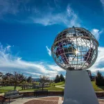 The sun peaks through a statue of the globe on campus. 