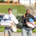 Two male students carry belongings to their dorm on move-in day. 