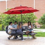Four students sit at a table with their computers studying outside. 