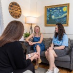 Two female college students visit with an advisor in the campus counseling center. 