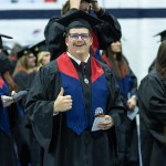 A male honors students gives a thumbs up just ahead of graduation services. 