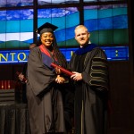 A female graduate accepts her diploma from President Young. 