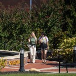 Two female students are walking in the quad while talking. 