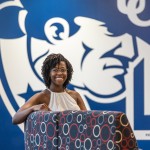 A female student sits in a chair in front of a wall with the Cumberlands logo in the student success center. 