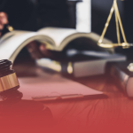 Judge Writing in Book with Gavel and Scales in Foreground