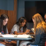 A group of students study together at a table in the library. 