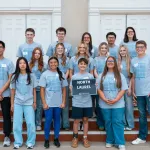 A group of high school students hold a sign with the school name on it at the annual math contest. 