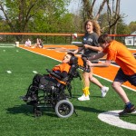 A male high school student, being coached by a Cumberlands student volunteer, pushes a child in a wheel chair during the 2026 Special Olympics.