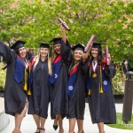 A group of five females in regalia celebrate with their diplomas following commencement services. 