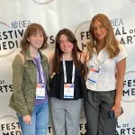 Three college newspaper staff members pose after winning an award. 