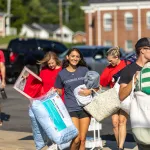 A freshmen female carries pillows from the parking lot to her dorm during move-in weekend. 