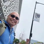 Cumberlands Cybersecurity Professor Elyson De La Cruz takes a selfie in a cityscape. 