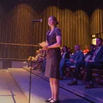 A female law student stands at a microphone and asks a question of Supreme Court members during a campus event. 
