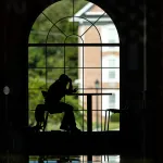A student is studying in the campus grille but is silhouetted against the window behind her. 