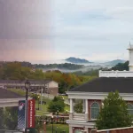 Fog rises above the university campus center during an early fall morning. 