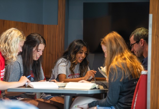 A group of students study together at a table in the library. 
