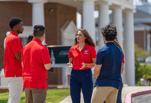 A female physical therapy student leads a discussion among a group of students. 
