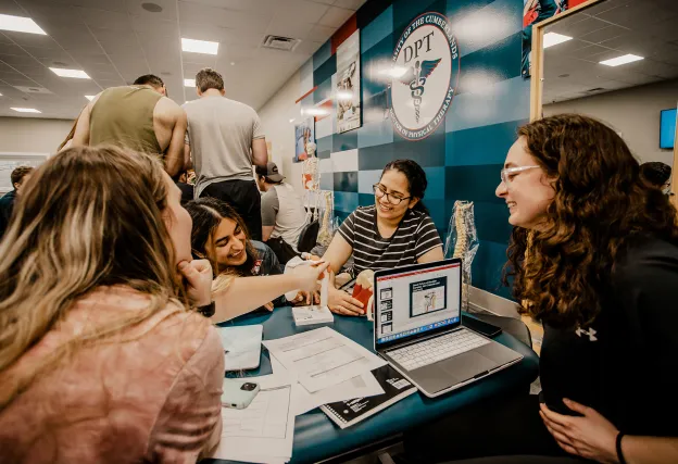 Four female physical therapy students work through a project in the PT lab. 