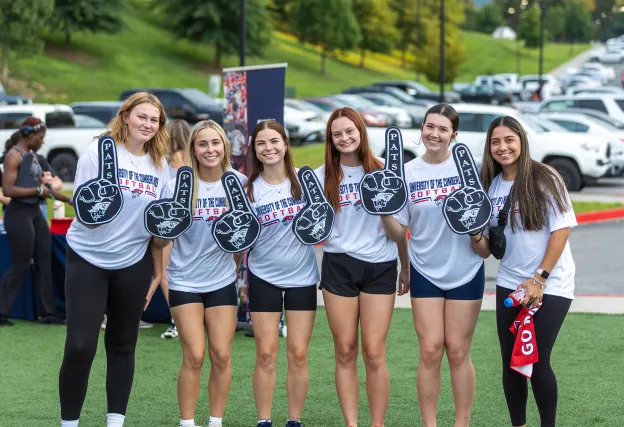 Six female students hold up Pats foam fingers during a welcome week event. 